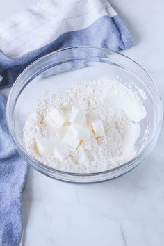 a bowl filled with flour and cubes on top of a white marble countertop