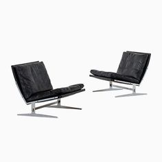 two black leather chairs sitting next to each other on top of a white flooring