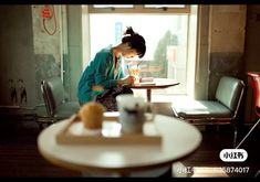 a woman sitting at a table in front of a window