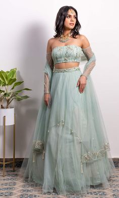 Editor's Note Off-shoulder Embroidered Blouse With Pearl Tasseled Lehenga And Dupatta Color: Green Fabric: Net, Shantoon Embroidery Details: Pearl, Sequins And Cut-dana Embroidery Care: Dry Clean Only About the Designer Founded by Silky Bindra, the couture brand under the label “Silky Bindra” is a very popular bridal wear option with chic, feminine, and elegant pieces, for any and every occasion. One Shoulder Lehenga, Off Shoulder Lehenga, Wedding Lehenga Designs, Full Sleeve Blouse, Green Lehenga, Net Lehenga, Embroidered Lehenga