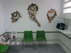 three pictures of cats on the wall behind green chairs