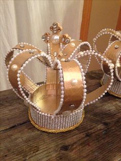 two tiaras sitting on top of a wooden table next to each other, one wearing pearls