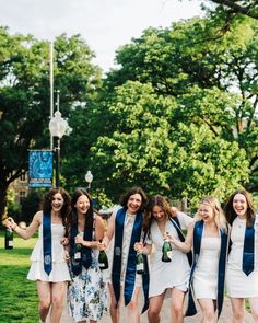 a group of young women standing next to each other in front of a tree filled park