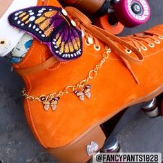 an orange shoe with butterflies on it and two roller skates next to each other