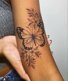 a woman's arm with a butterfly and flowers tattoo design on the left forearm