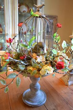 a birdcage filled with flowers on top of a wooden table