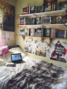 a laptop computer sitting on top of a bed in a room filled with books and posters