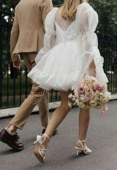 a man and woman are walking down the street with flowers in their hand while wearing wedding shoes