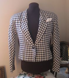 "Classic Blazer Vintage ladies size 4 in navy and cream fitted tapered bodice, broad textured weave, single fabric covered button at waist, Cropped length classic houndstooth, lapel chest pockets with folded and pinned hankie, fully lined, shoulders are  padded, lapels are rather wide, gently flared from waist button to bottom. Size Ladies/Misses Size 4 Fabric 40% silk 30% wool 20% Rayon 10% nylon Color Navy and cream large scale houndstooth  Made in  USA Waist 32\" Bottom 38\" at button flair B Fitted Houndstooth Tweed Jacket With Lapel Collar, Fitted Houndstooth Tweed Jacket With Long Sleeves, Fitted Long Sleeve Houndstooth Tweed Jacket, Fitted Semi-formal Outerwear With Houndstooth Pattern, Fitted Vintage Houndstooth Blazer, Classic Double-breasted Houndstooth Blazer, Vintage Fitted Houndstooth Blazer, Fitted Houndstooth Button-up Outerwear, Luxury Long-sleeve Houndstooth Blazer