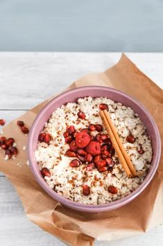 a pink bowl filled with rice and cranberries on top of a wooden table