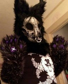 a person wearing a cat costume with black fur and purple flowers on their chests