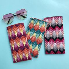 three pieces of colorful knitted cloth with sunglasses on top and one piece in the shape of a zigzag