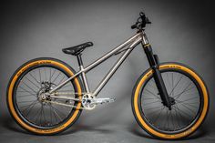 a silver and orange bike is shown against a gray background with yellow rims on it