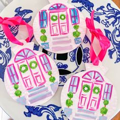 three paper plates decorated with pink and green doors