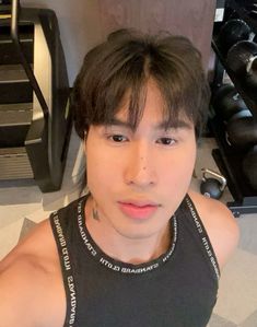 a young man is posing for the camera in front of some dumbbells and exercise equipment