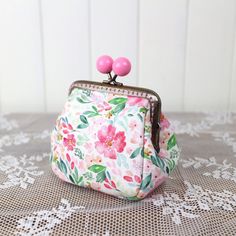 a pink flowered purse sitting on top of a lace tablecloth covered table cloth