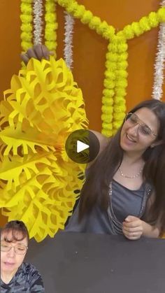 a woman standing next to a little boy in front of a yellow flower decoration on a wall