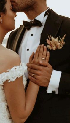 a bride and groom kissing each other in front of the ocean on their wedding day