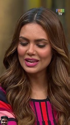 a close up of a person with long hair wearing a pink and black striped shirt