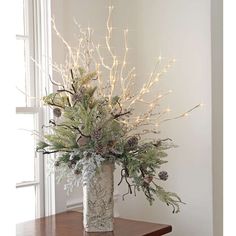 a vase filled with lots of greenery on top of a wooden table