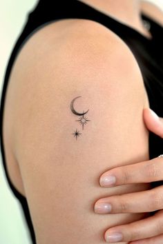 a woman's arm with a crescent and stars tattoo on the left side of her shoulder