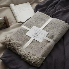 an open book on top of a bed next to a blanket and pillow with a cross