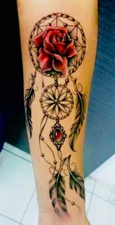 a woman's arm with a rose and dream catcher tattoo on it