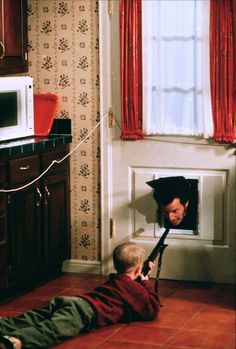 a little boy laying on the floor in front of a window with an umbrella over his head