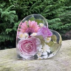 a heart shaped vase filled with flowers on top of a wooden table