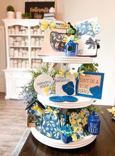 three tiered cake stand with cards and decorations on it's sides, sitting on a wooden table