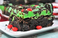 a white plate topped with cake covered in green frosting and red candy candies