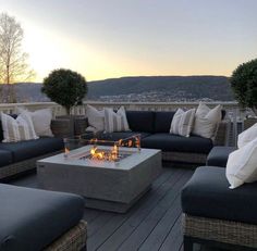 a fire pit sitting on top of a wooden deck next to couches and pillows