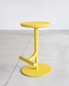 a yellow stool sitting on top of a cement floor