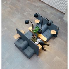 a person sitting on a couch reading a book in a room with grey tile flooring