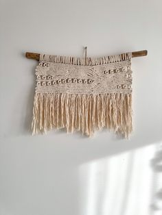 the wall hanging is made from yarn and wooden dows, which are hung on a white wall