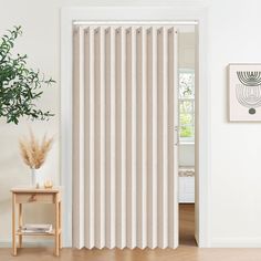 a living room with white walls and beige vertical blinds on the sliding glass door that are open