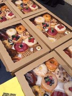 four boxes filled with assorted donuts on top of a table