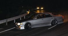 a silver car driving down a road at night with fog coming from its exhaust system