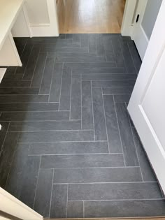 an empty kitchen with gray tile flooring and white cabinets on either side of the door