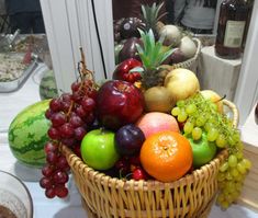 a wicker basket filled with lots of different types of fruit on a white table