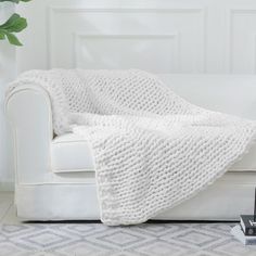 a white couch with a blanket on top of it next to a book and remote control