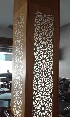 an intricate wooden screen is in the middle of a room with black chairs and tables