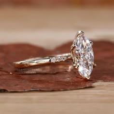 a diamond ring sitting on top of a piece of brown leafy wood with leaves around it