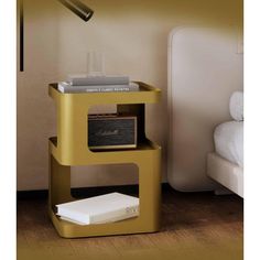 a nightstand with a radio on it next to a white bed and a gold lamp