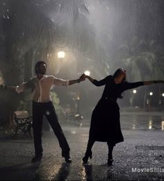 a man and woman dancing in the rain with their arms outstretched, one holding the other's hand