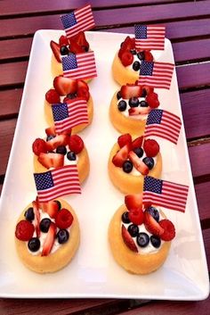 patriotic desserts with strawberries and blueberries are arranged on a white platter