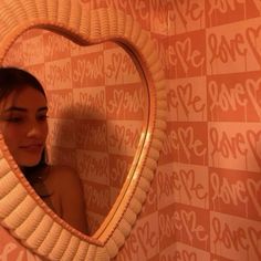 a woman is looking into a mirror with the word love written on it and there is a heart shaped mirror in front of her