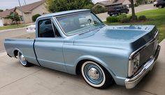 an old blue pickup truck parked on the side of the road in front of a house