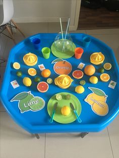 a child's play table with oranges, lemons and cups on it