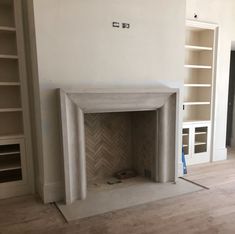 an empty living room with a fireplace and bookcases